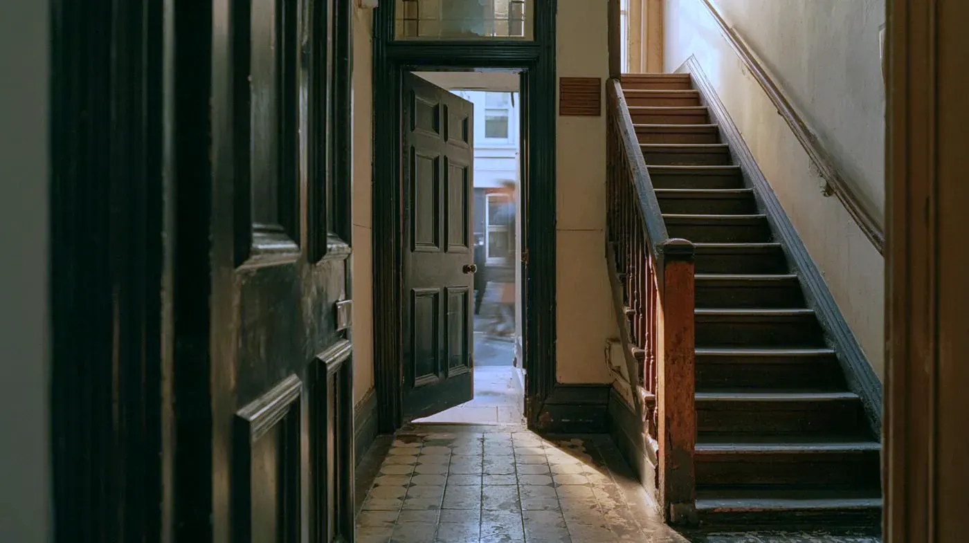 The entrance hall: tiled floor, the front door open onto the street, and stairs running up to the first floor.